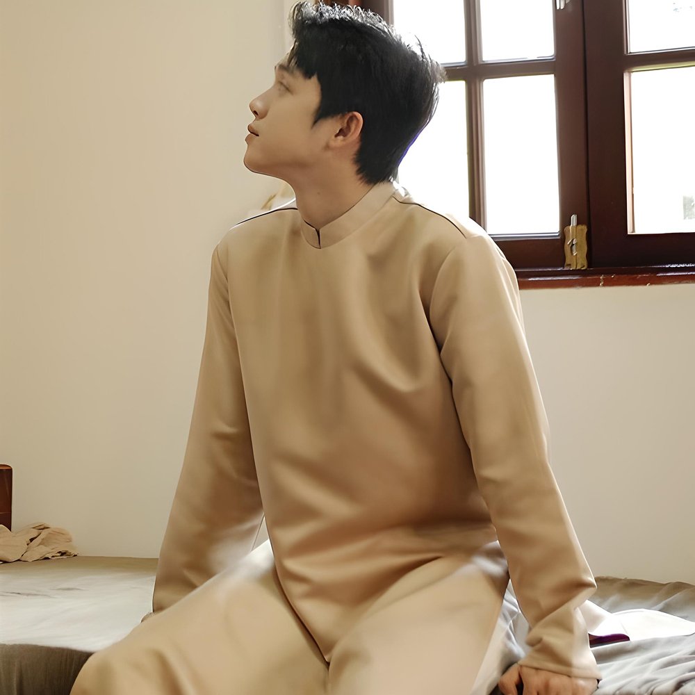 Áo Dài Nam Trơn Nâu Vàng ấm áp, form cách tân hiện đại, sử dụng Vải Tafta cứng giúp áo đứng dáng tuyệt đối. Thiết kế không họa tiết, tôn vinh sự tối giản, lịch lãm và cổ điển. Màu Nâu Vàng (Nâu Đất/Vàng Đất) lý tưởng cho chú rể, các sự kiện mùa Thu Đ